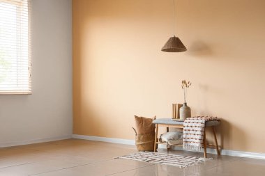 Çimenli vazo, kitap ve ekose bej duvarın yanındaki odada.