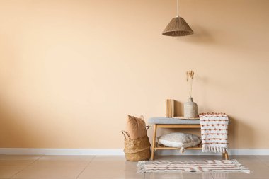 Çimenli vazo, kitap ve ekose bej duvarın yanındaki odada.