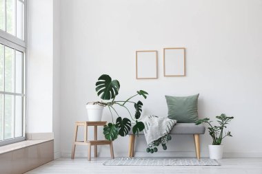 Yumuşak bank, boş çerçeve ve bitkilerle aydınlatma odasının içi