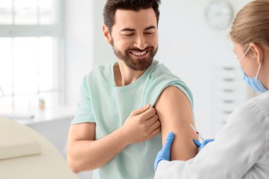 Genç adam klinikteki doktordan aşı alıyor.