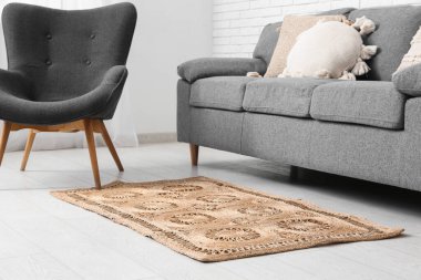 Beyaz tuğla duvarın yanında kanepe, koltuk ve hasır halıyla oturma odasının içinde.