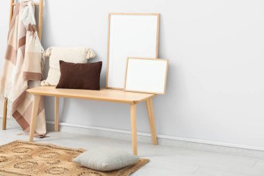 Beyaz duvarın yanında ahşap bank, merdiven, çerçeve ve hasır halı olan oturma odasının içinde.