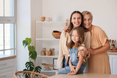 Annesi ve büyükannesiyle mutfakta kucaklaşan küçük kız.