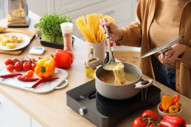 Genç kadın mutfakta erişte çorbası yapıyor.