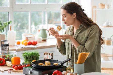 Genç bir kadın mutfakta kızarmış mısır üflüyor.