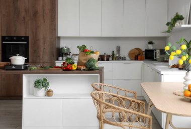 Mutfağın içinde masalar, tezgahlar ve taze ürünler var.