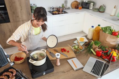 Genç kadın mutfaktaki masada erişte çorbası yapıyor.