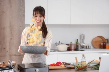 Genç bir kadın mutfakta patates kızartıyor.