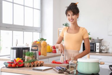 Mutfakta masada biber kesen genç bir kadın.