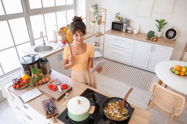 Mutfakta tablet bilgisayarı olan genç bir kadın.