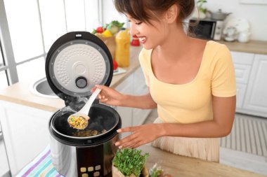 Genç bir kadın mutfakta çoklu fırın kullanıyor.