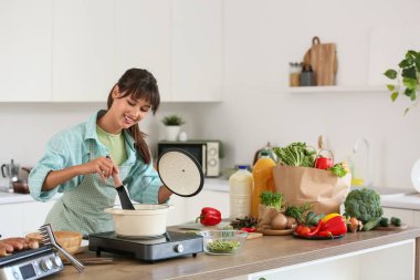 Genç kadın mutfakta erişte çorbası yapıyor.