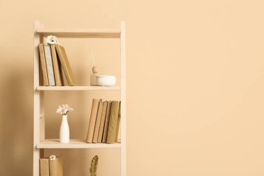 Bej duvarın yanında çiçekli kitaplık