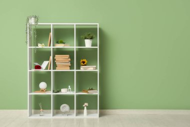 Yeşil duvarın yanında çiçekli kitaplık