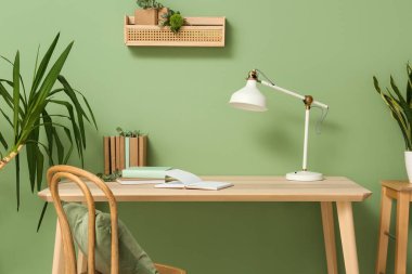 Kitaplar, lamba ve okaliptüs dallarıyla dolu bir masa.