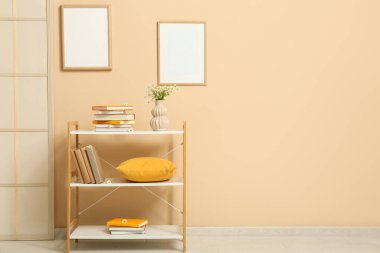 Odada bej duvarın yanında papatya çayı olan bir kitaplık.