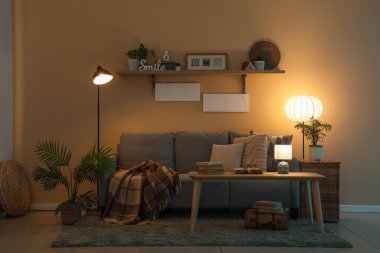 Geceleri parıldayan lambaları, kanepesi ve masası olan karanlık oturma odasının içinde.