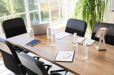 Masasında tablet bilgisayar ve su şişeleri olan dizüstü bilgisayar konferans salonundaki iş toplantısı için hazırlandı.