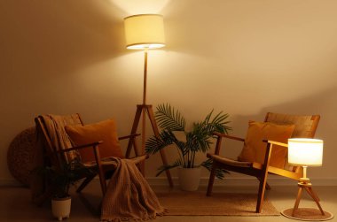 Geceleri parıldayan lambalar, koltuklar ve palmiye bitkileriyle oturma odasının içinde.