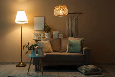 Geceleri parıldayan lambaları, kanepesi ve masaları olan karanlık oturma odasının içinde.