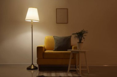 Parlak lambalı, sarı koltuklu ve gece masalı karanlık oturma odasının içi.