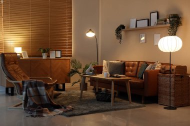 Geceleri parıldayan lambaları, koltuğu ve koltuğu olan karanlık oturma odasının içinde.