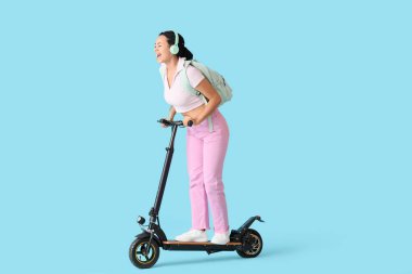 Mavi arka planda elektrikli scooter kullanan kulaklıklı Afro-Amerikan bir kız öğrenci.