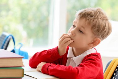 Sınıfta masa başında çivi yiyen küçük bir öğrenci.