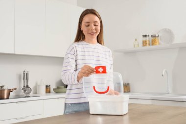 Mutfakta açık ilk yardım çantası olan genç bir kadın.