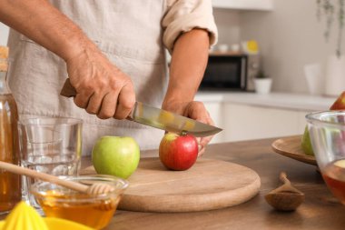 Mutfakta elma suyu için elma kesen olgun bir adam, yakın plan.