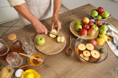 Mutfakta elma suyu için elma kesen olgun bir adam.