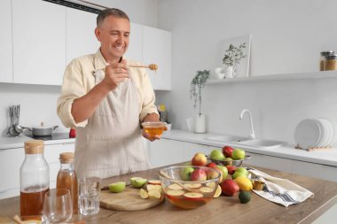 Mutfakta elma suyu yapan ballı olgun bir adam.