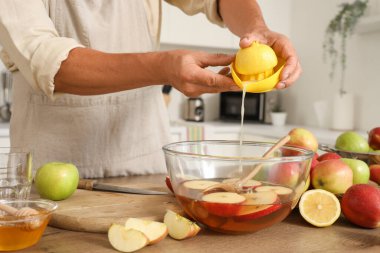 Mutfakta elma suyu için limon sıkan olgun bir adam, yakın plan.