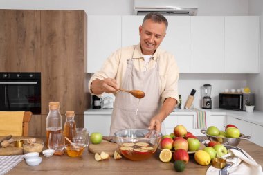 Olgun bir adam mutfakta elma şarabı yapıyor.