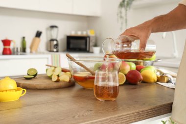 Olgun bir adam mutfaktaki cama elma şarabı döküyor.