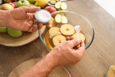 Mutfaktaki masada elma suyu yapan şekerli erkek elleri, yakın plan.