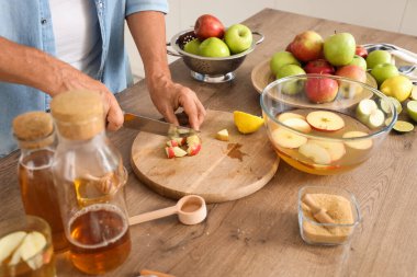 Mutfakta elma suyu için elma kesen olgun bir adam, yakın plan.