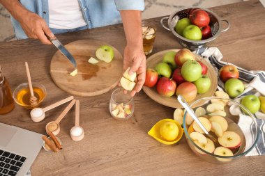 Mutfakta elma suyu için elma kesen olgun bir adam.