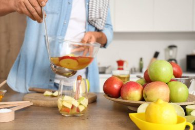 Olgun bir adam mutfaktaki cama elma şarabı döküyor.