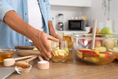 Olgun bir adam mutfaktaki masadan elma şırası alıyor, yakın plan.
