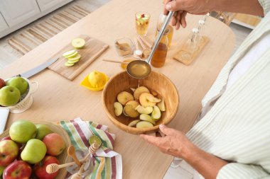 Mutfaktaki masada elma şarabı yapan olgun bir adam.