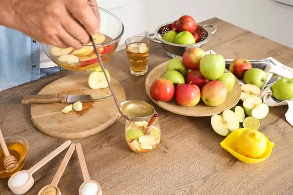 Olgun bir adam mutfaktaki cama elma şarabı döküyor.