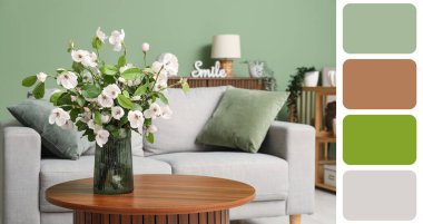 Gri kanepesi, masası ve çiçek açan ağaç dallarıyla dolu oturma odası. Farklı renk desenleri