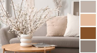 İçinde çiçek açan ağaç dalları ve dergiler olan vazo oturma odasının içindeki masada. Farklı renk desenleri