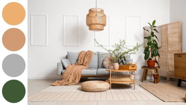 Oturma odasının içinde gri kanepe, masa ve ağaç dalları vazoda. Farklı renk desenleri