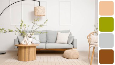 Oturma odasının içinde gri kanepe, masa ve ağaç dalları vazolarda. Farklı renk desenleri