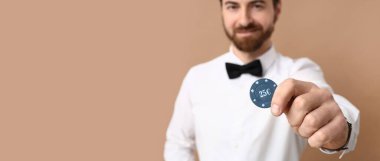 Bej arkaplanda çipi olan yakışıklı erkek poker oyuncusu metin için boşluk, yakın plan