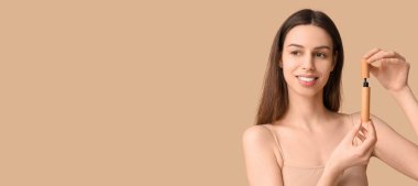 Kahverengi arkaplanda rimel tutan genç ve güzel bir kadın.