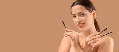 Kahverengi arka planda rimel tutan genç ve güzel bir kadın.