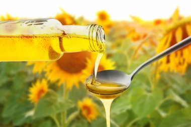 Beyaz arka planda şişeden kaşığa taze zeytinyağı dökülüyor.